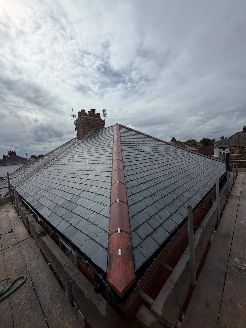 Natural slate hip roof with red ridge tiles and a brick chimney