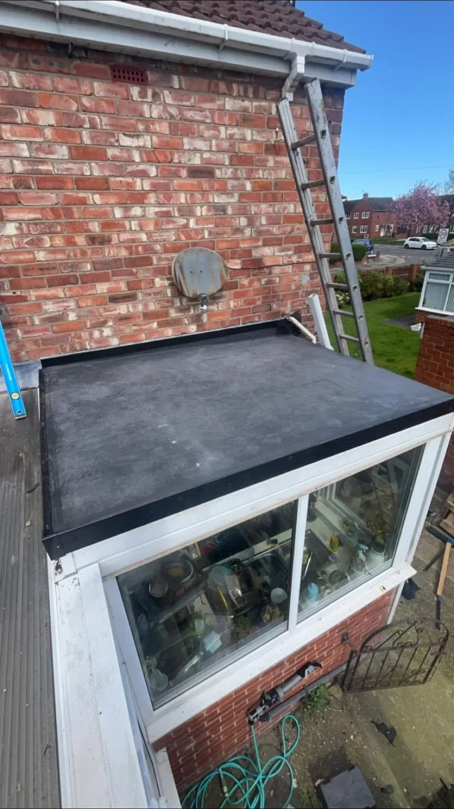 Flat roof over a glazed extension adjoining a brick wall