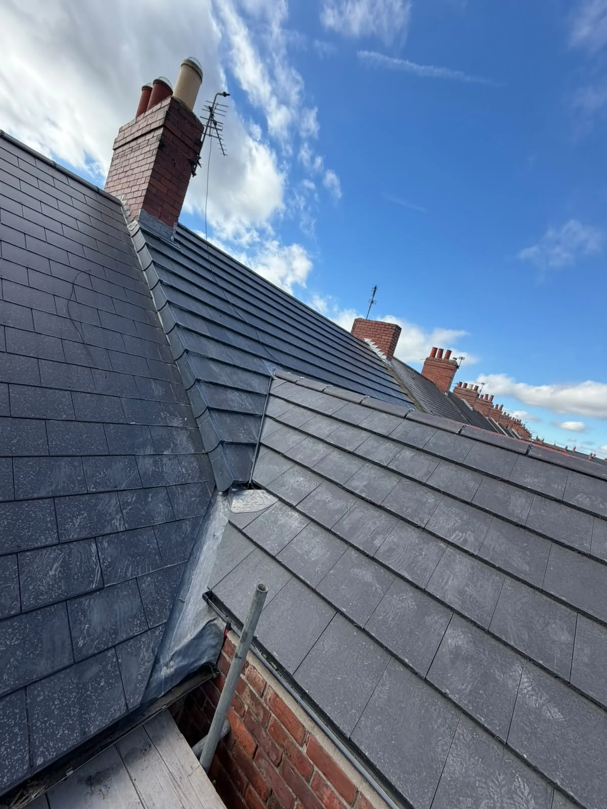 Slate roof with a brick chimney and lead valley
