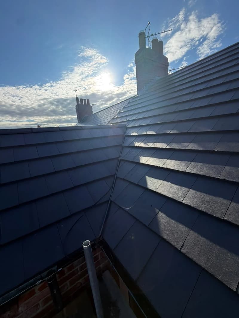 Tiled roof valley and brick chimney in sunlight