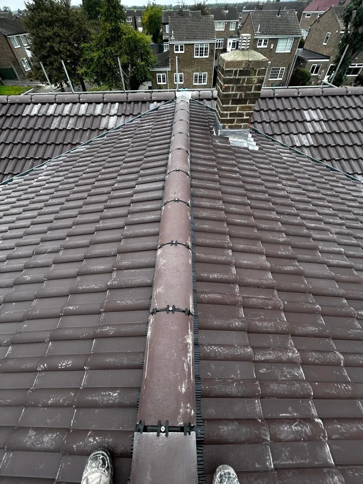 Brown tiled roof with a ridge and brick chimney stack