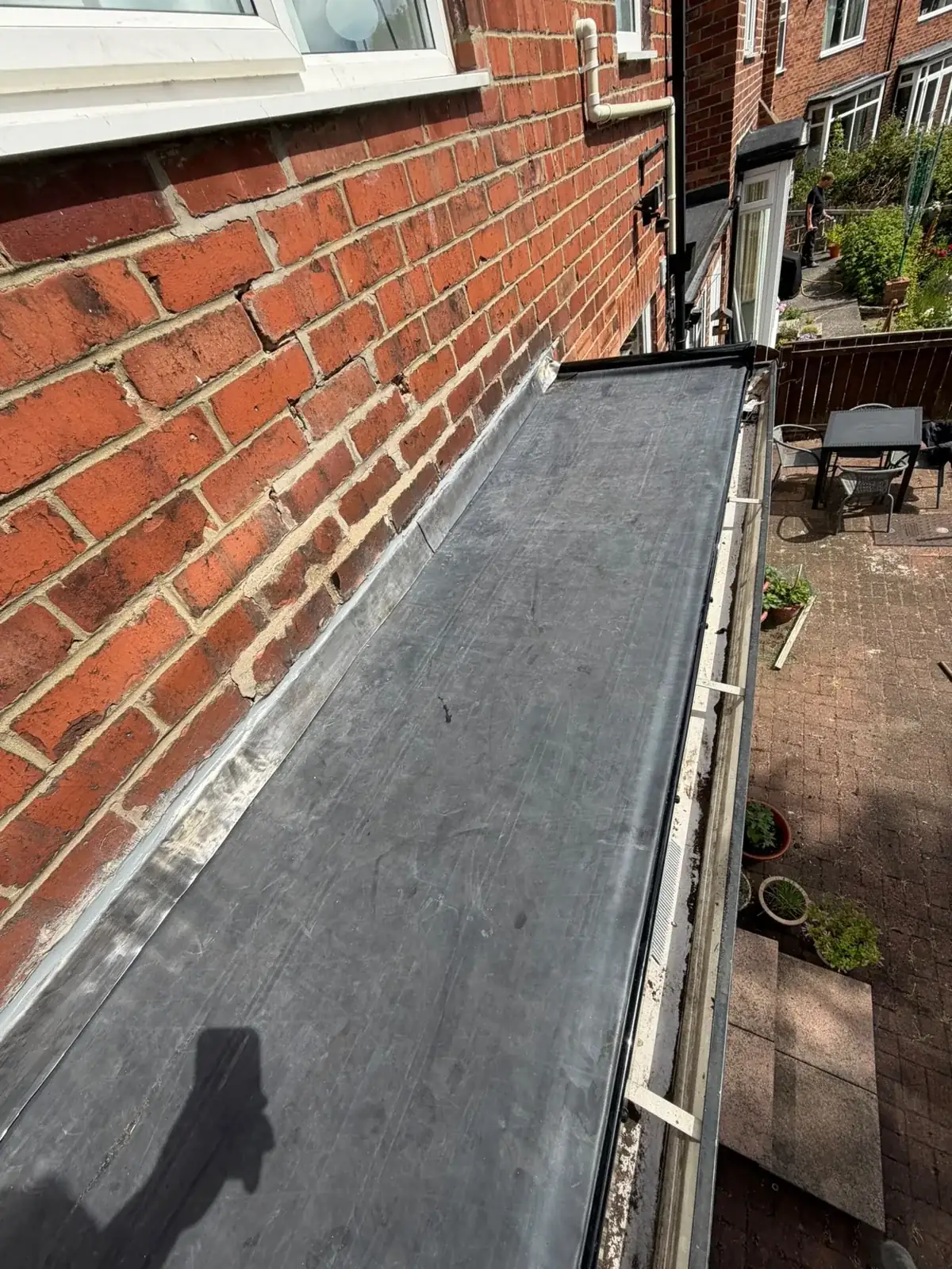 EPDM flat roof with lead flashing against a brick wall